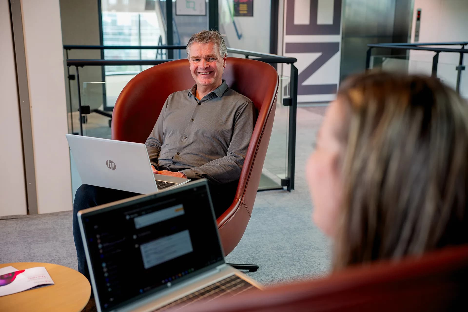Twee personen voeren een formeel gesprek met laptops voor zich