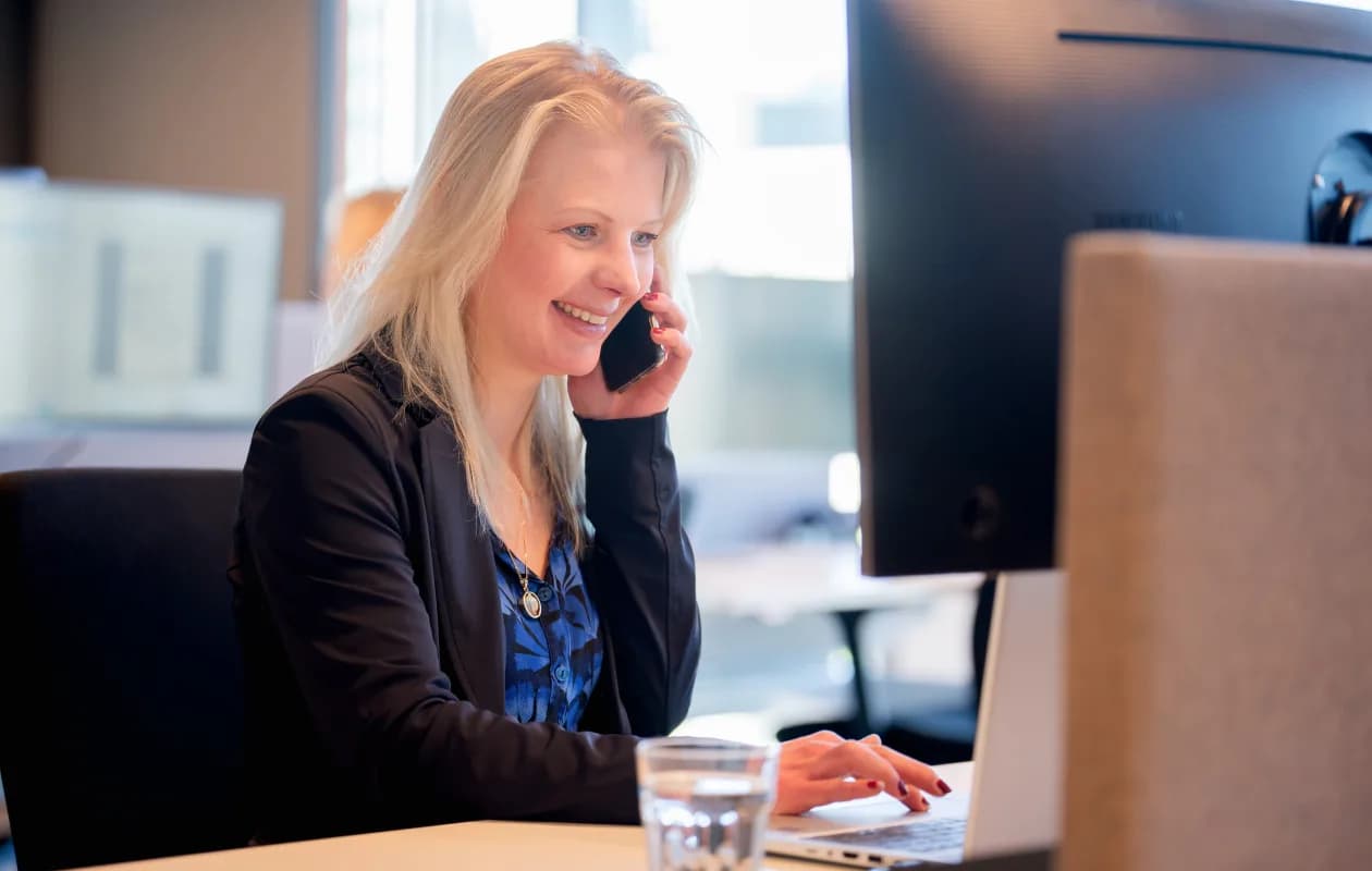 Person on the phone, laughing, with a laptop in front of them