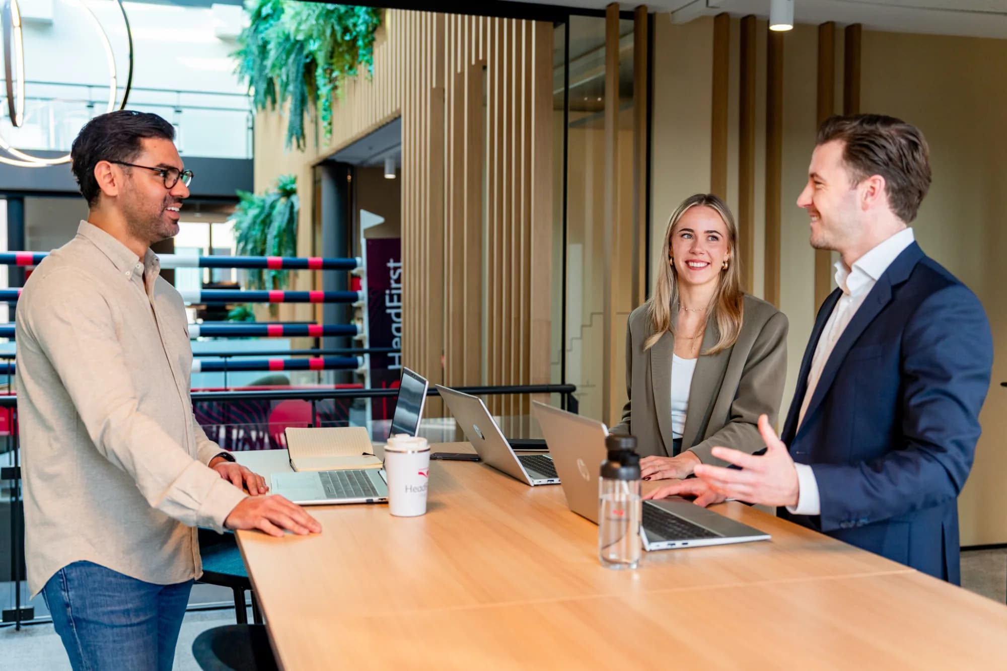 Three people in an office meeting, discussing tariff developments per profession.