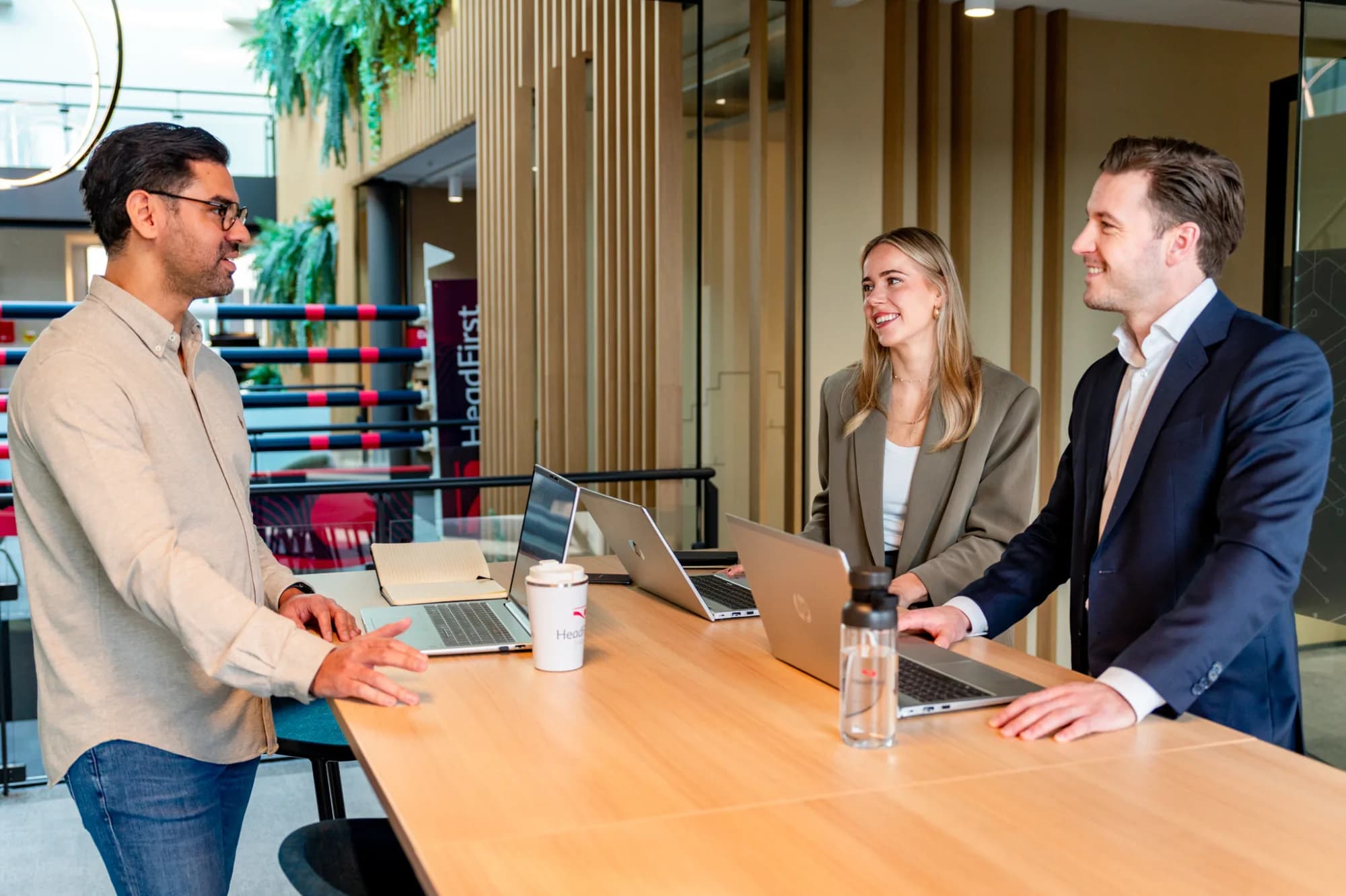 3 colllegas in overleg met laptops aan een statafel