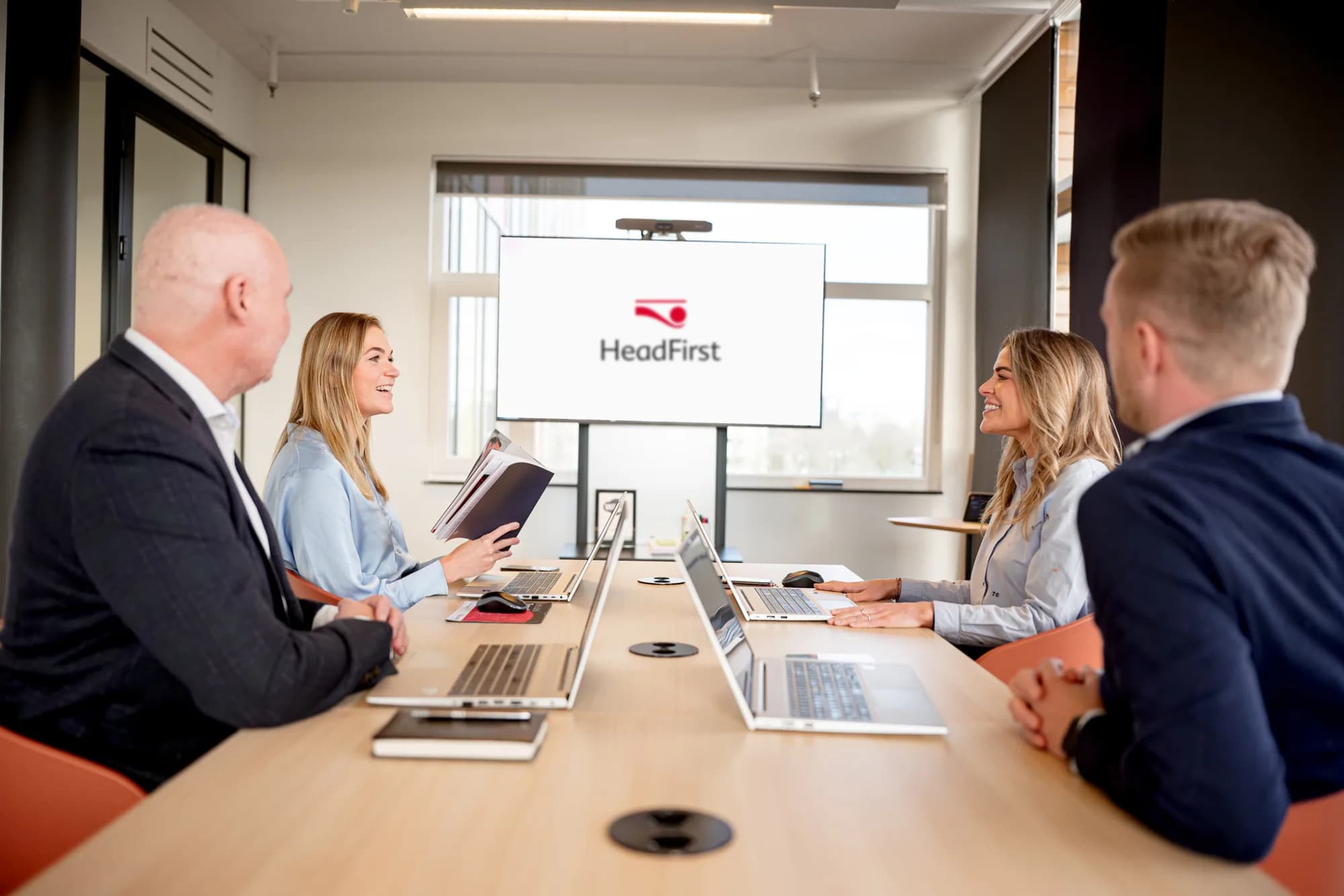 Office meeting with a team around a table full of laptops